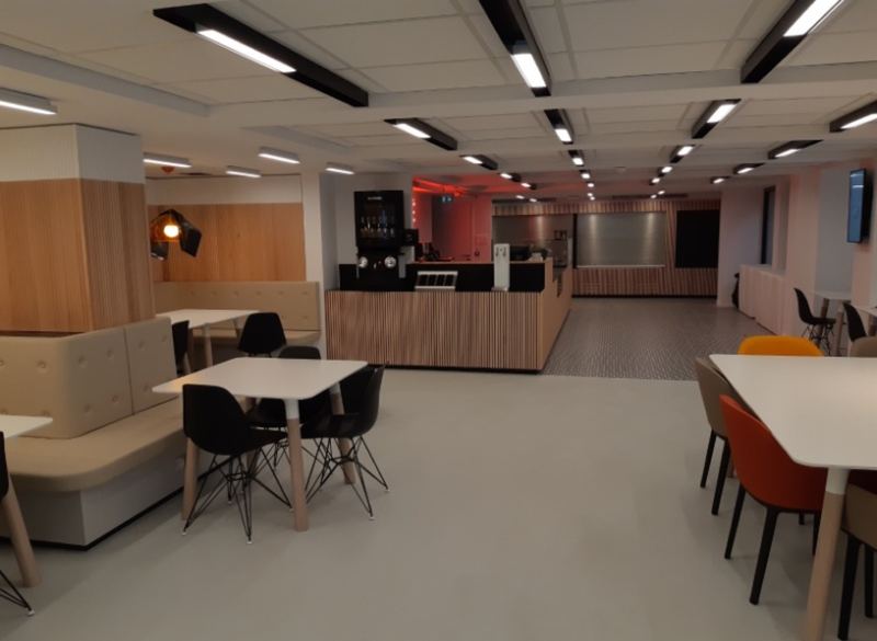 Salle de restaurant collectif avec habillage bois, comptoir et mobilier